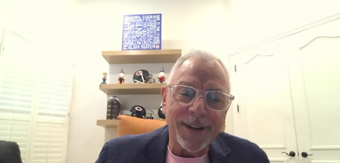 Alex Iuorio in office wearing navy blue sport coat, pink t-shirt and clear-framed glasses