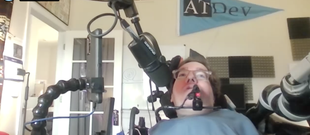Owen Kent sitting in his mobility device speaking into the microphone during the interview.
